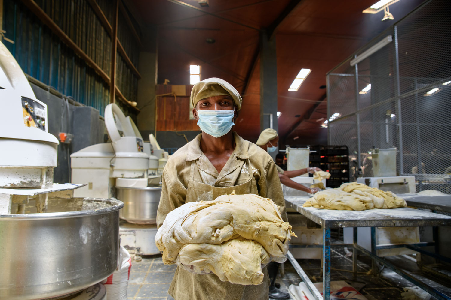 Charles Mambo, 26yrs with over 9yrs of baking getting dough out of the mixer | Malawi