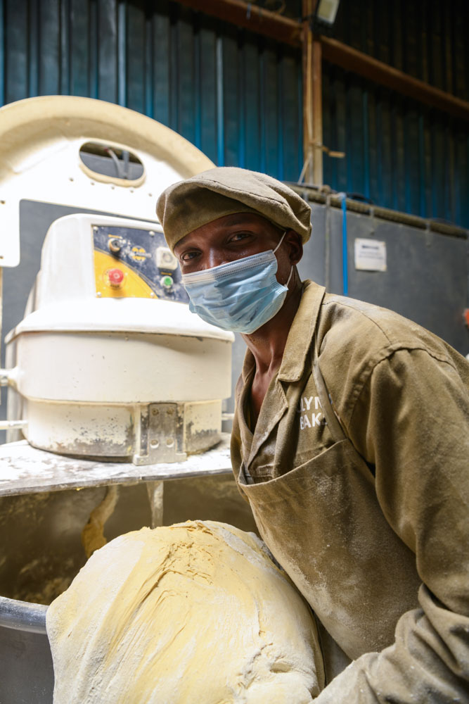 Charles Mambo, 26yrs with over 9yrs of baking getting dough out of the mixer | Malawi